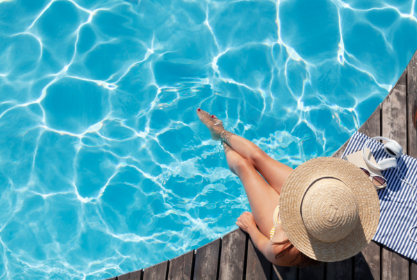 Woman sitting at the edge of a pool with her feet in the water for a blog post addressing cellulite concerns