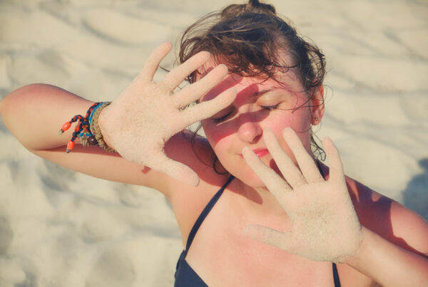 Girl blocking her face from the sun with her hands.