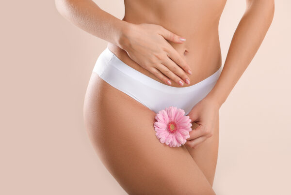 Young woman with flower on light background. Vaginal restoration inference.